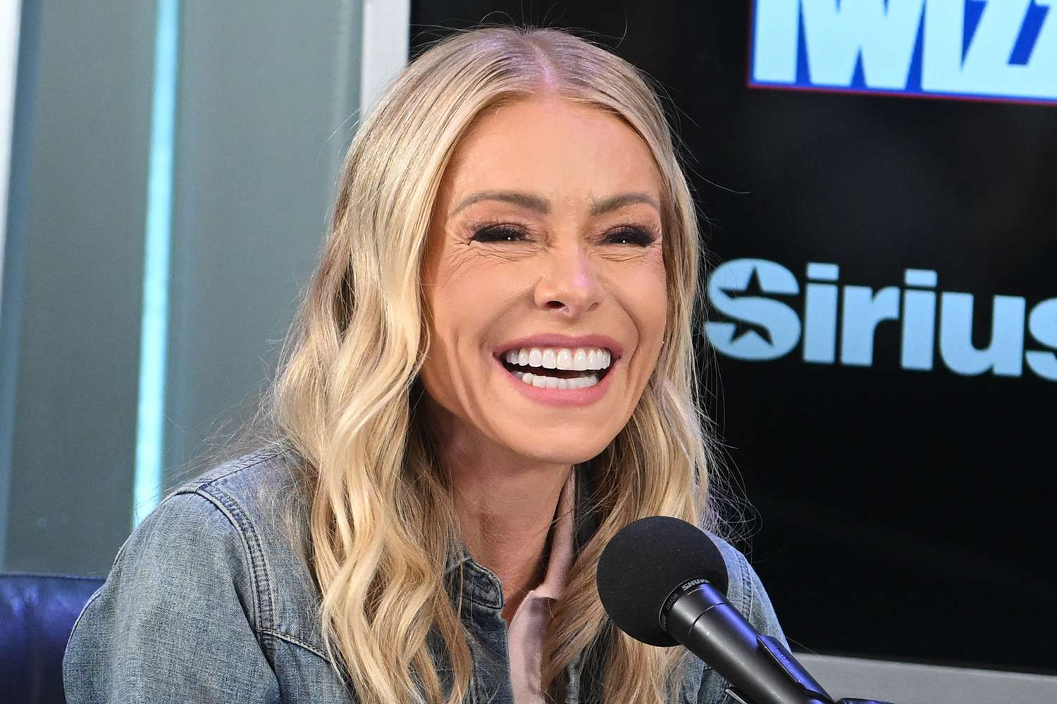 Kelly Ripa and Mark Consuelos smiling together as Ripa discusses her gum graft surgery and recovery from gum recession.