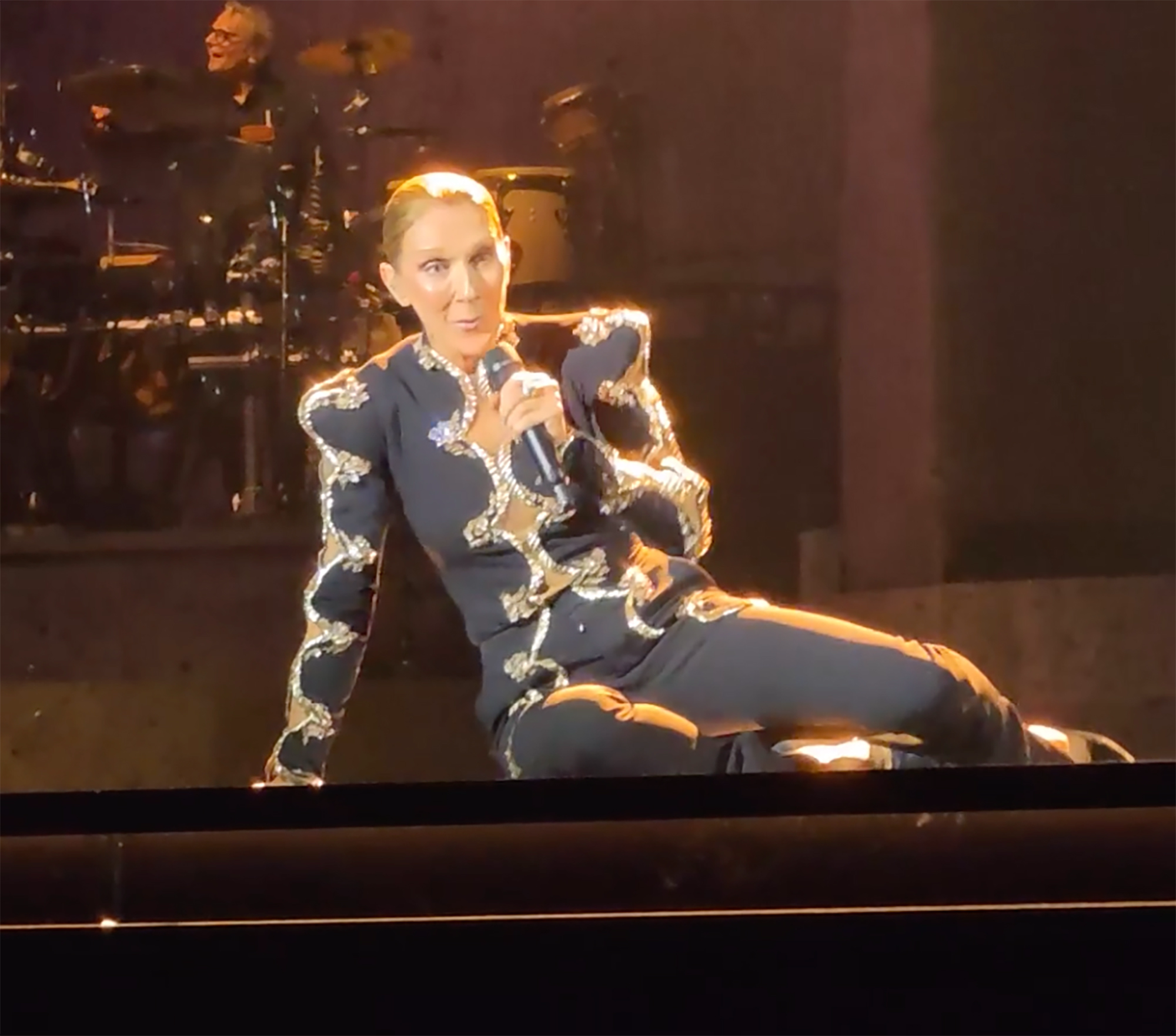 Celine Dion performs onstage during her Paris concert, where she fell mid-song before quickly getting back up and continuing the show.